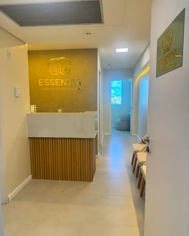 Recepção da Essentia com balcão de madeira e a marca da clínica na parede